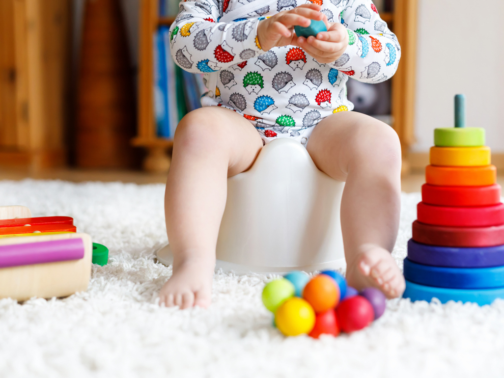 child sitting on a toilet with toys