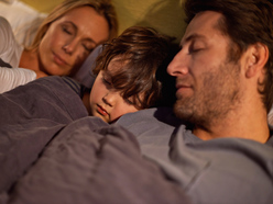 A child sleeping between their parents