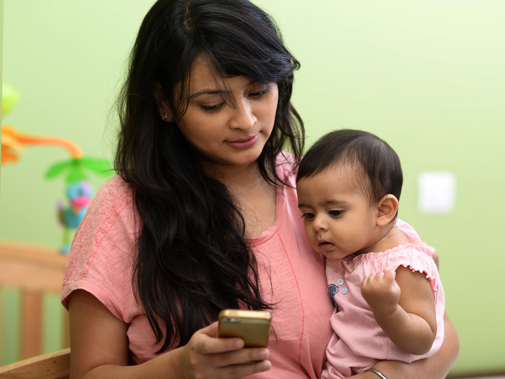 Bebê olha o celular com a mãe