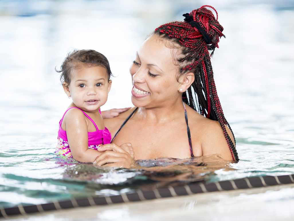 Mulher negra segura bebê negro na piscina 