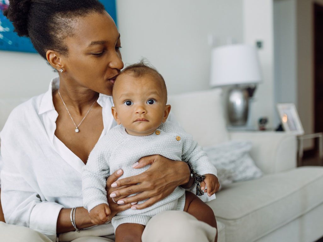 Mulher negra beija a cabeça de bebê negro