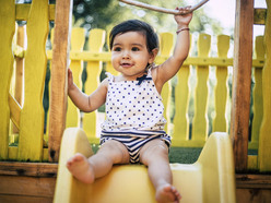 niña sonriendo sentada en un resbalador