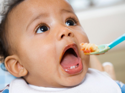 baby opening their mouth to eat a spoonful of food