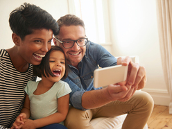 happy couple with a girl in the middle taking selfies