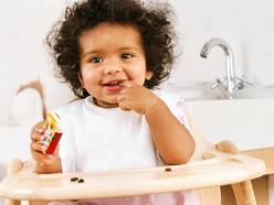 19 month old sitting in her highchair and feeding herself raisins