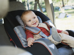 smiling toddler sitting in a front-facing car seat