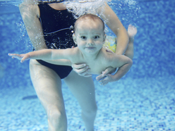 baby swimming underwater and being held by a woman