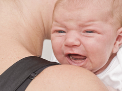 Baby crying on mum's shoulder