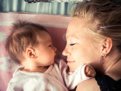 Smiling mum lying in bed with new born