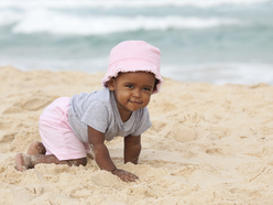 Older baby crawling on beach