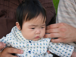 Baby sat in mum's arms, looking serious