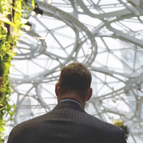 An image of the back of a man in a suit walking inside The Seattle Spheres at Amazon’s headquarters.