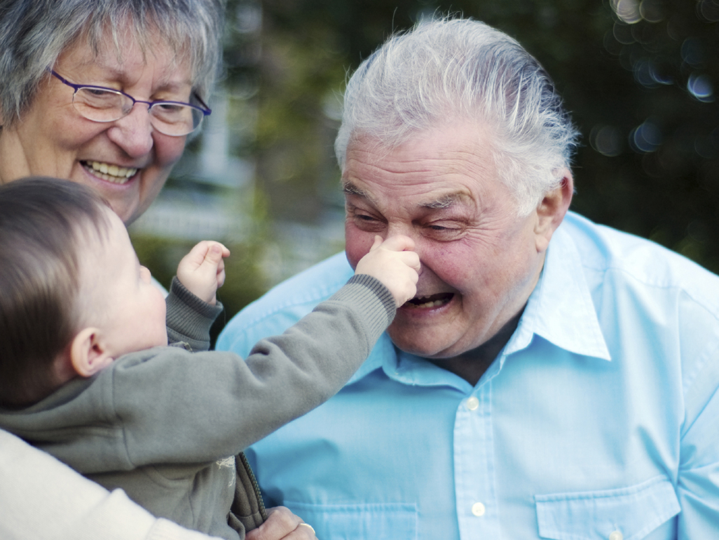 A baby grabbing the nose of a laughing grandparent