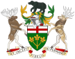 A central shield with the upper part showing the red cross of St. George and the lower part showing three golden maple leaves on a green background. There is a black bear on top of a knight's helmet above the shield with a moose to the left and a Canadian deer to the right. The province's motto "Ut incepit Fidelis sic permanent", Latin for "Loyal she began, loyal she remains" is written below the crest.