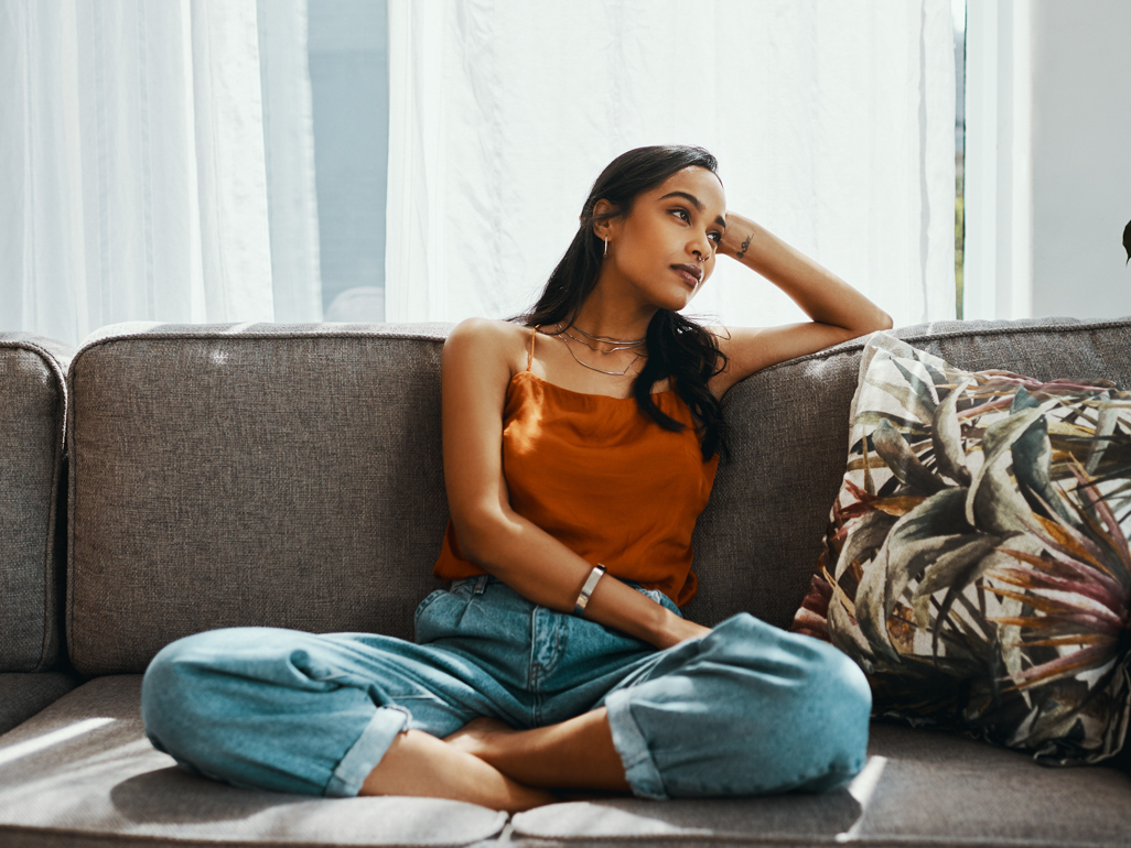 thoughtful woman sitting on the couch looking away