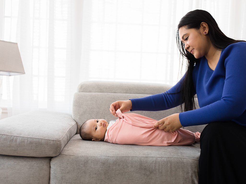 A mom swaddling a baby in a pink blanket