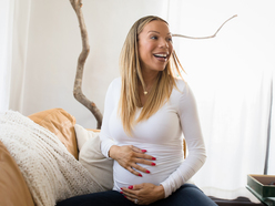 pregnant woman laughing while holding belly