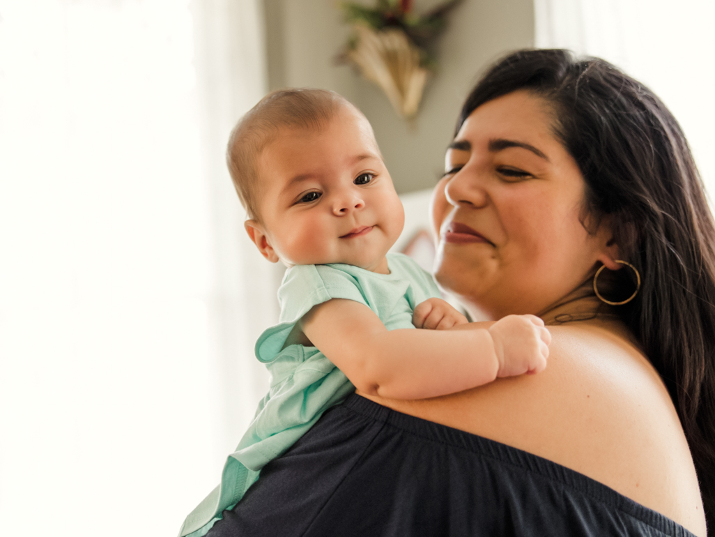 Mulher sorri com bebê no colo