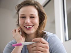 smiling woman looking at a pregnancy test