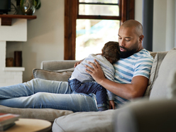 A father with a sleeping toddler on his lap