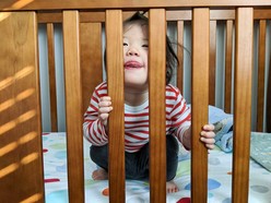 A toddler sitting up in a crib