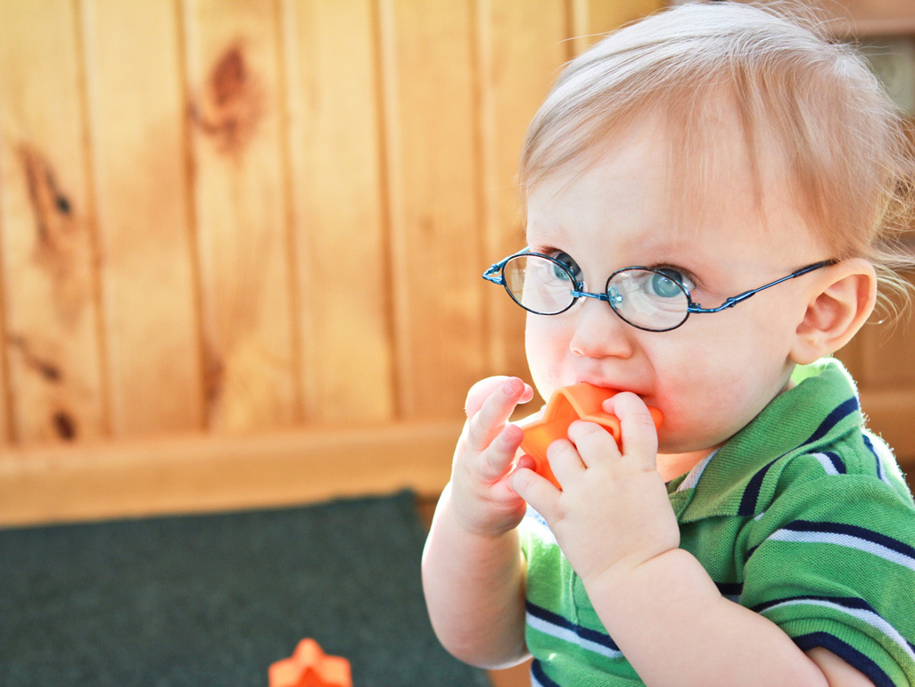 child with glasses biting plastic star toy