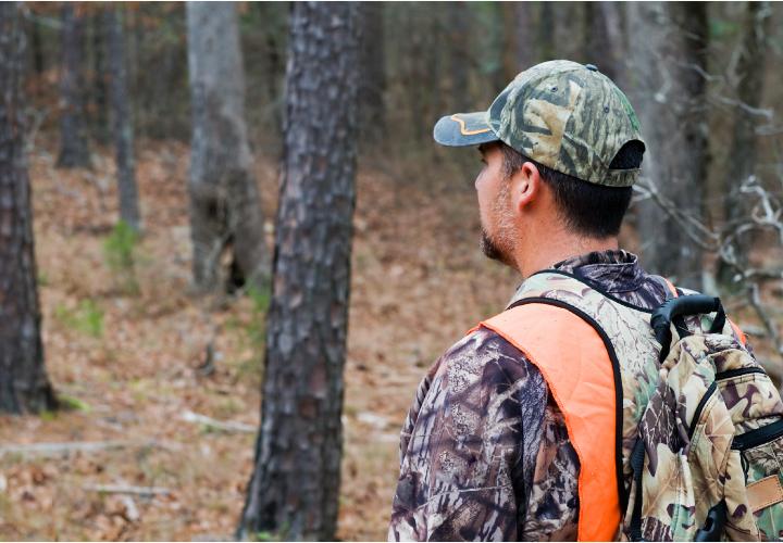 Adult male deer hunting in the woods with orange safety vest