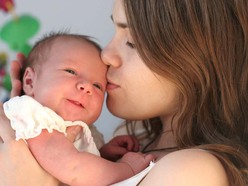 Mom holding newborn baby and kissing their head