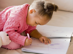 Toddler scribbling on a book with a pen