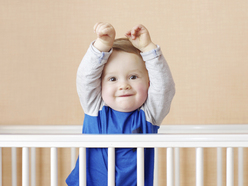 Baby standing up, stretching in crib