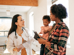 Mom holding toddler daughter and talking to doctor