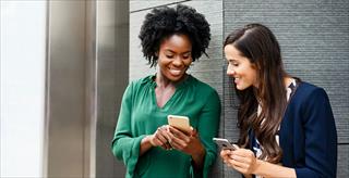 two women sharing content on their smartphones