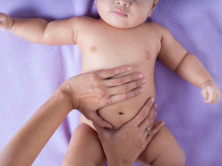 Mum's hands on baby's tummy around belly button