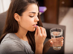 Woman taking a pill with a glass of water