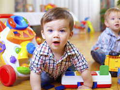 Toddler boy surrounded by toys.