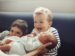 Zwei kleine Jungen freuen sich über ein Neugeborenes