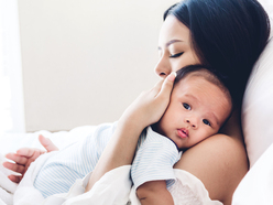 Woman holding her baby close in bed