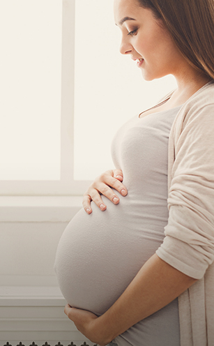 woman smiling and holding bump