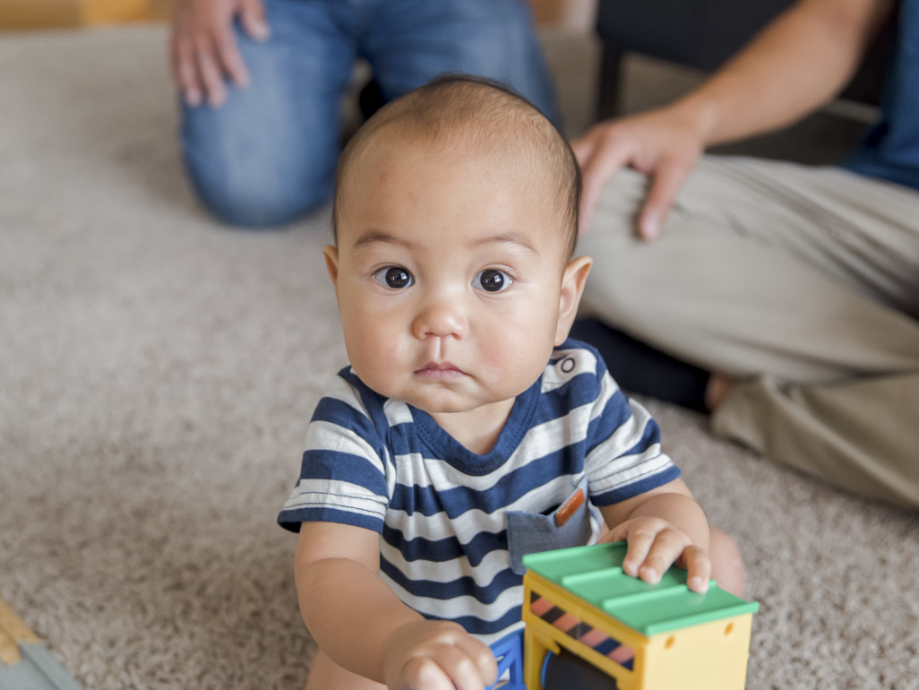 baby with striped shirt holding toy