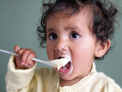 Baby feeding themselves porridge