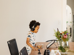 Toddler boy using wireless headphones and watching a tablet