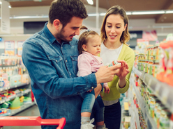 Couple with baby looking at label on food jar in shop