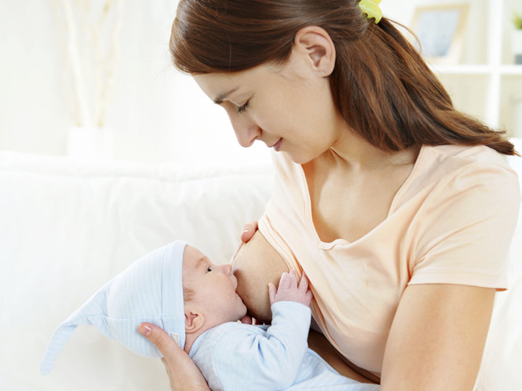 Woman breastfeeding a baby in a blue hat