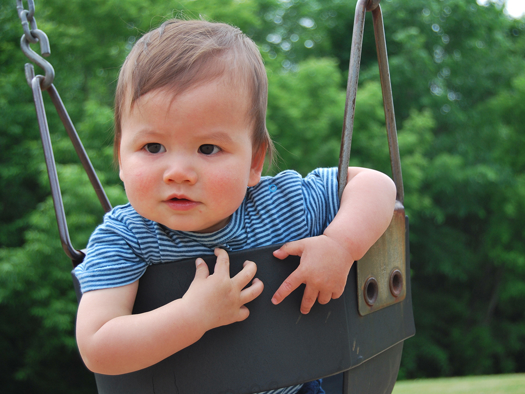 baby boy sat in an outdoor swing seat