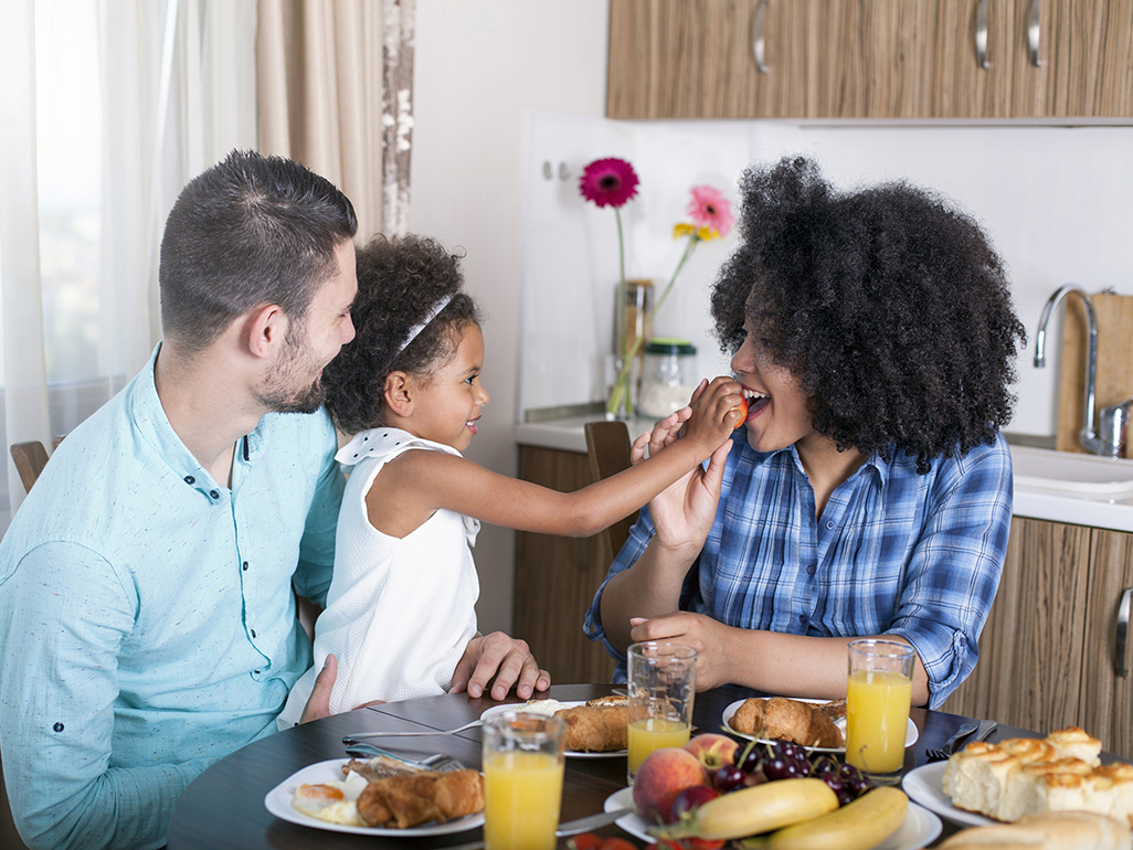 Parents and preschooler sitting down and eating breakfast