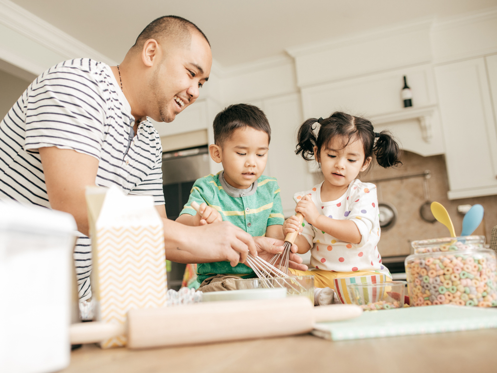 Dad making a cake in the kitchen with two children