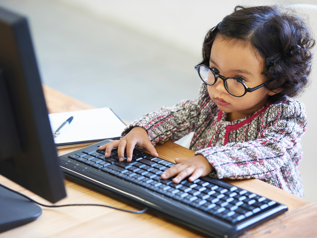 Toddler with glasses working on a computer