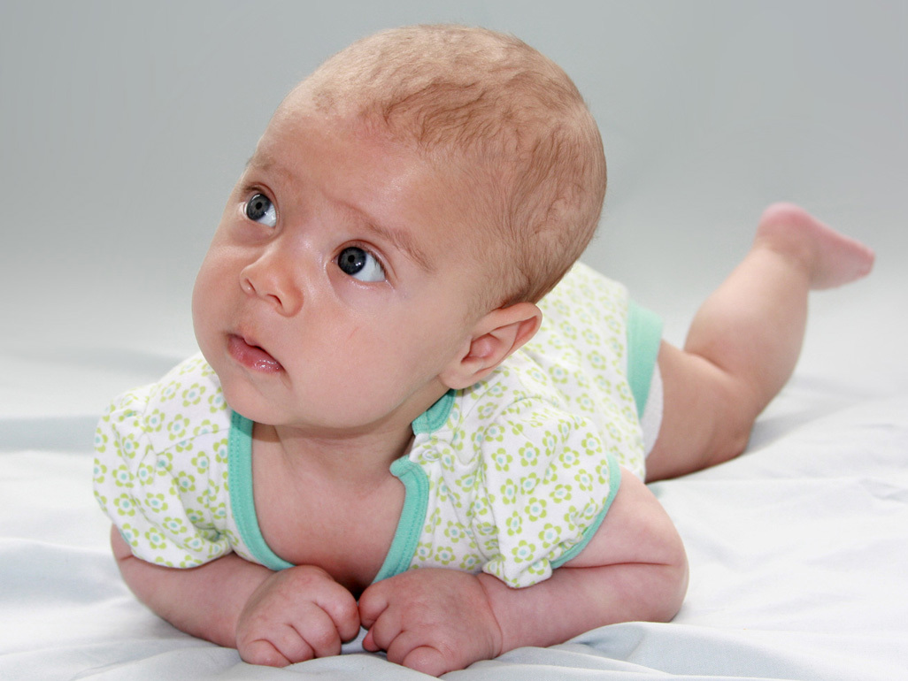 Three month old baby lying on blanket looking up