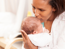 Mutter küsst ihr Baby auf den Kopf