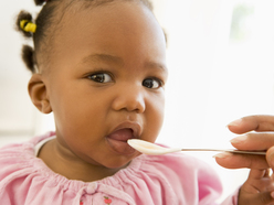 girl being fed from a plastic spoon